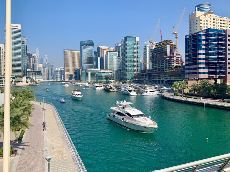 Scenic view of Dubai Marina canal with luxury yachts and high-rise modern skyscrapers